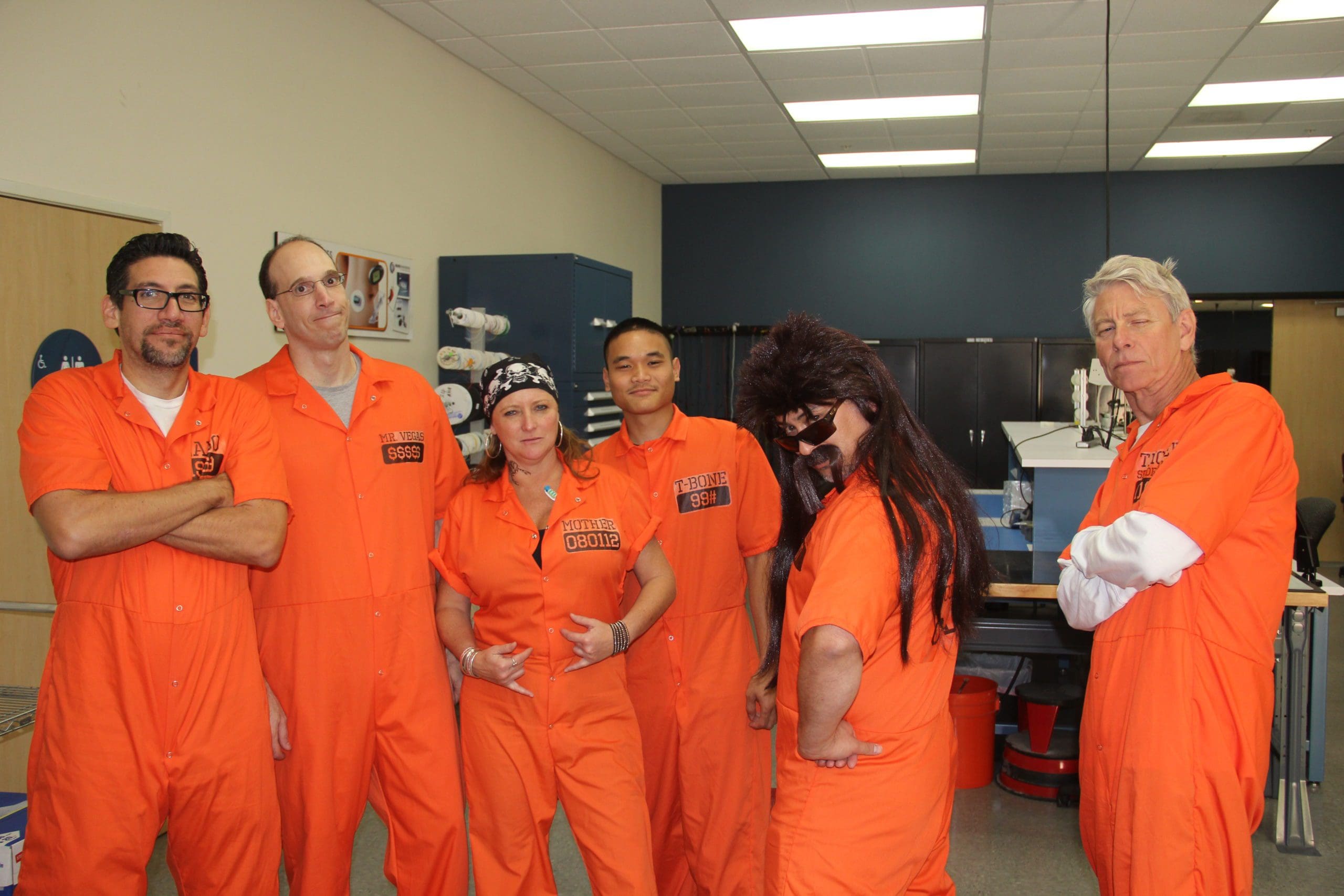 engineering team members dressed up for Halloween in orange jump suits like prison inmates